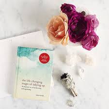 Image of Marie Kondo's book the Life changing magic of tidying up displayed near a vase of vibrant flowers as featured in article "Just say no" on mariedeveaux.com career coach